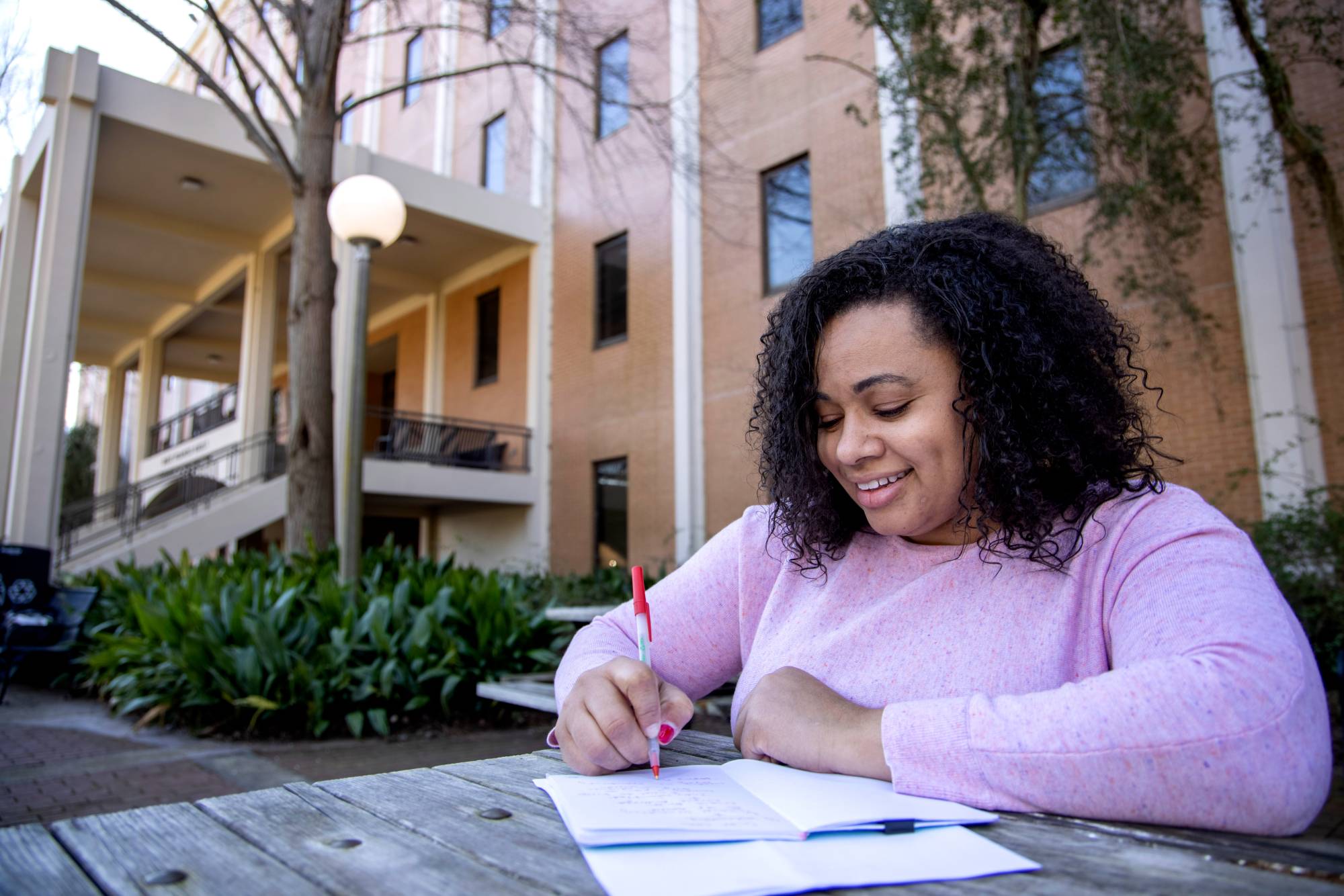 Gradate student Ashley Love studying at a table outside Aderhold Hall.